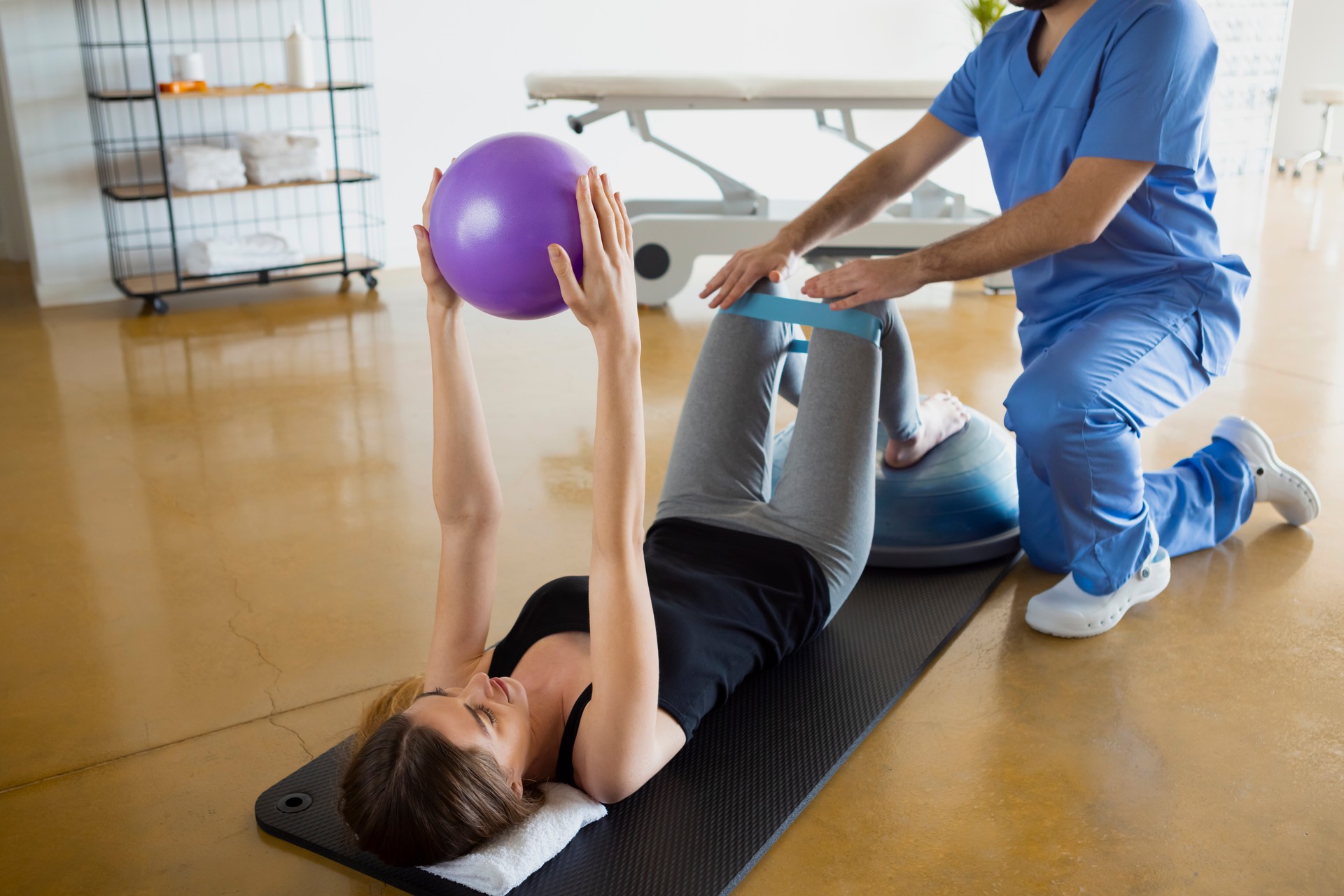 Female patient lying down on a mat exercising with her physiologist